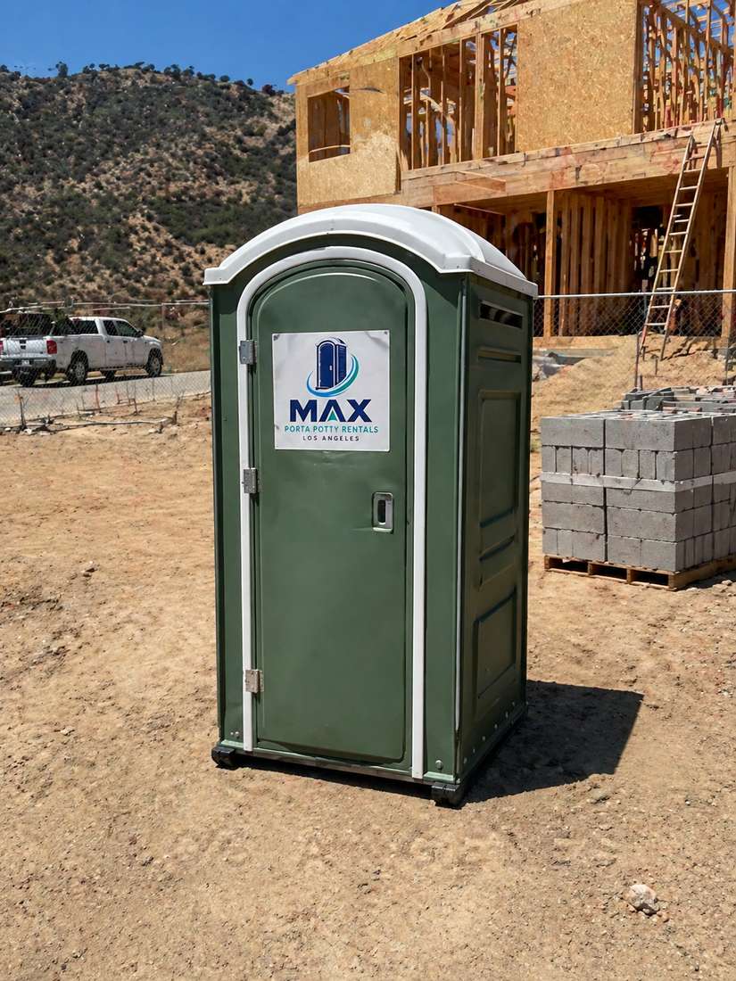 Green porta potty at a residential construction site